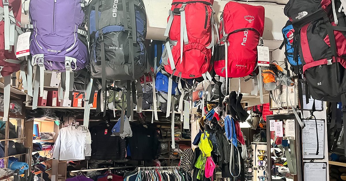 Backpacks, jackets, and trekking gear displayed inside a trekking shop in Pokhara, Nepal, offering equipment for hikers.