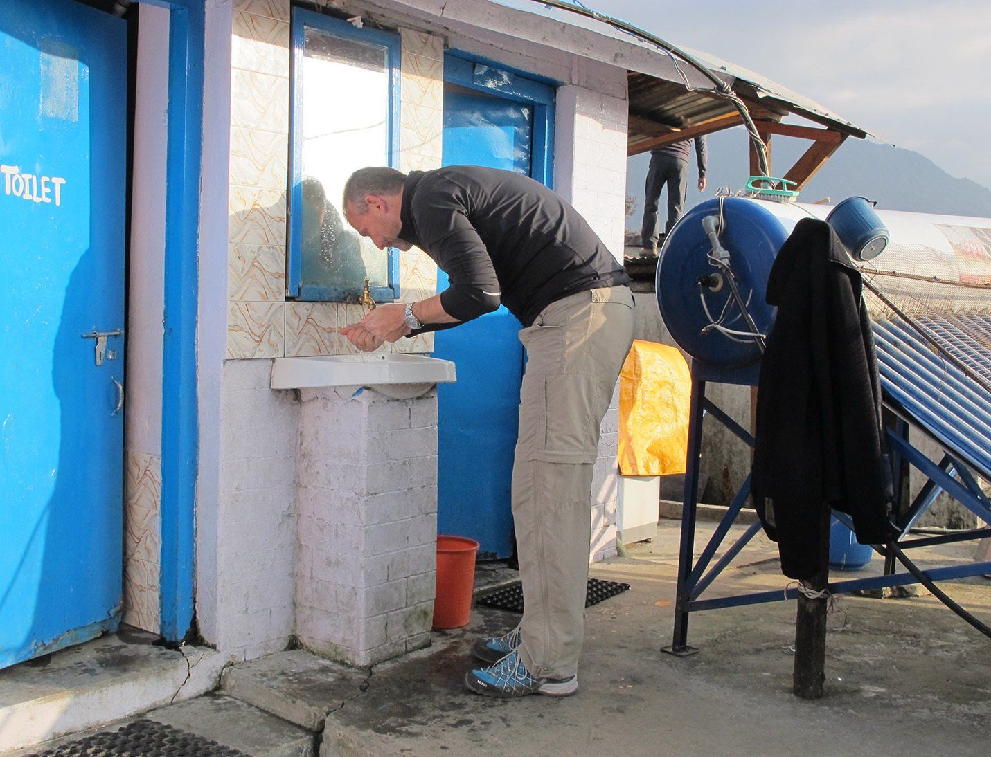Trekker using an outdoor washing station at a lodge on the Annapurna Trek in Nepal.