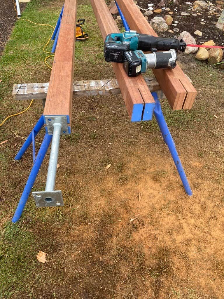 Two Wooden Beams on Blue Sawhorses, Construction Tools Laid on Top — Kalora Carpentry & Restorations in Charlestown, NSW