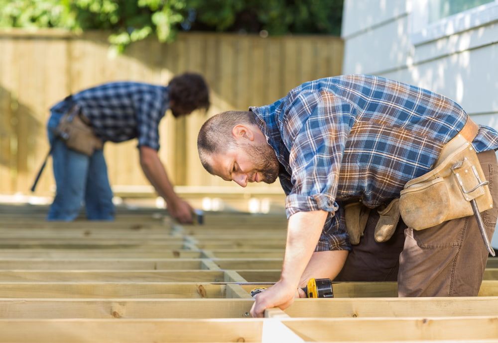 Two Men Building a Wooden Deck Outdoors; Focused, Using Tools — Kalora Carpentry & Restorations in Charlestown, NSW