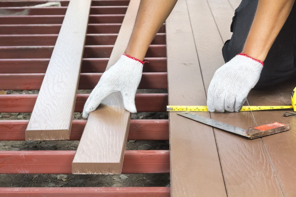 Person Measuring and Placing Wooden Planks on a Deck Frame — Kalora Carpentry & Restorations in Charlestown, NSW