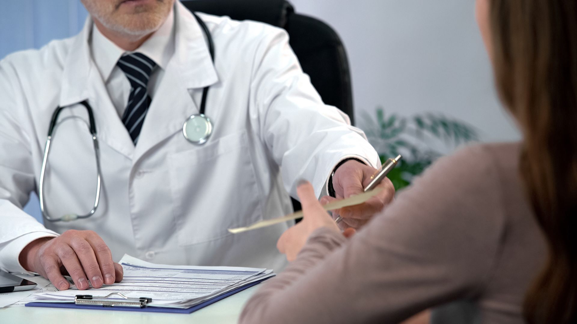 A doctor is talking to a patient while sitting at a desk.