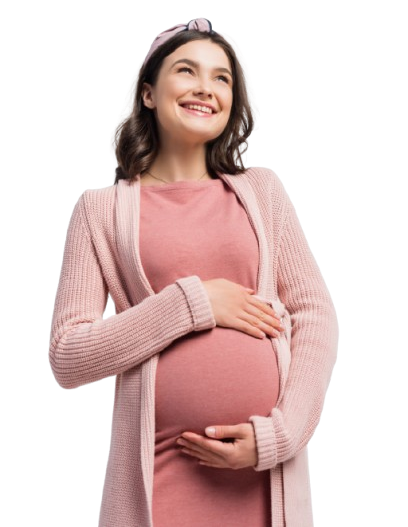 A pregnant woman in a pink dress is holding her belly and smiling.
