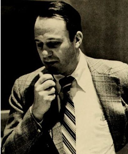 A man in a suit and tie is talking into a microphone