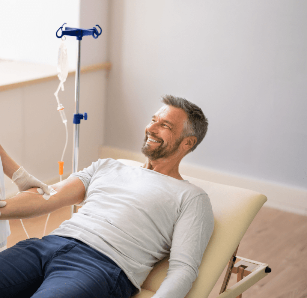 A man is laying in a hospital bed with an iv in his arm.