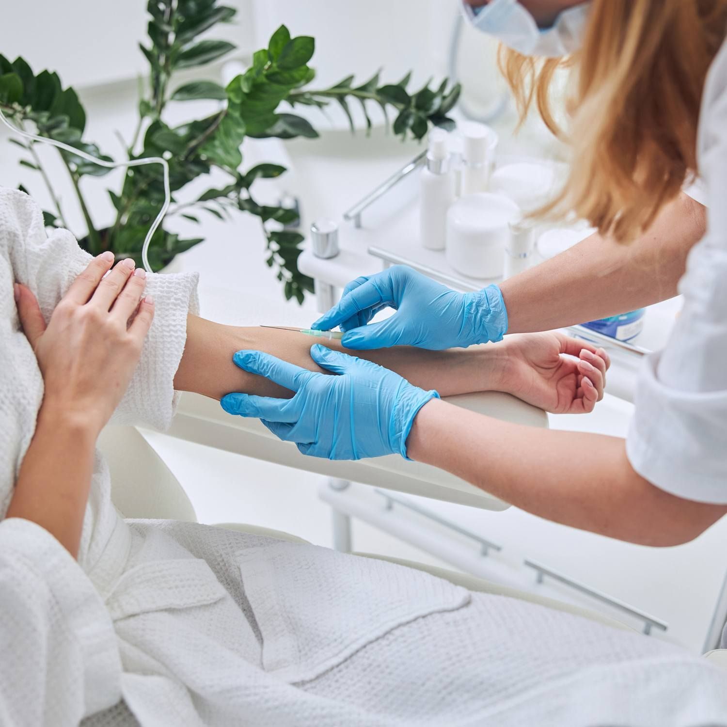 A woman wearing blue gloves is getting a treatment on her arm.