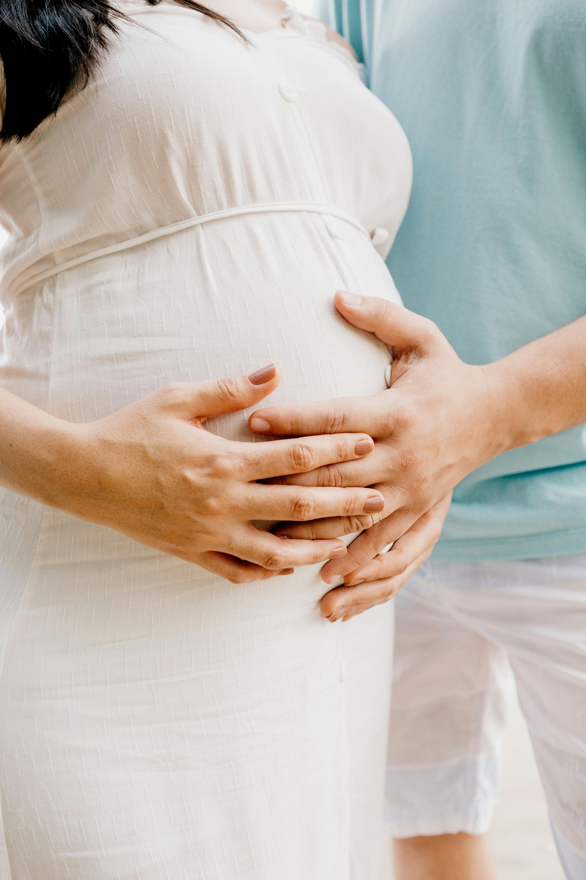 A pregnant woman and a man are holding her belly.