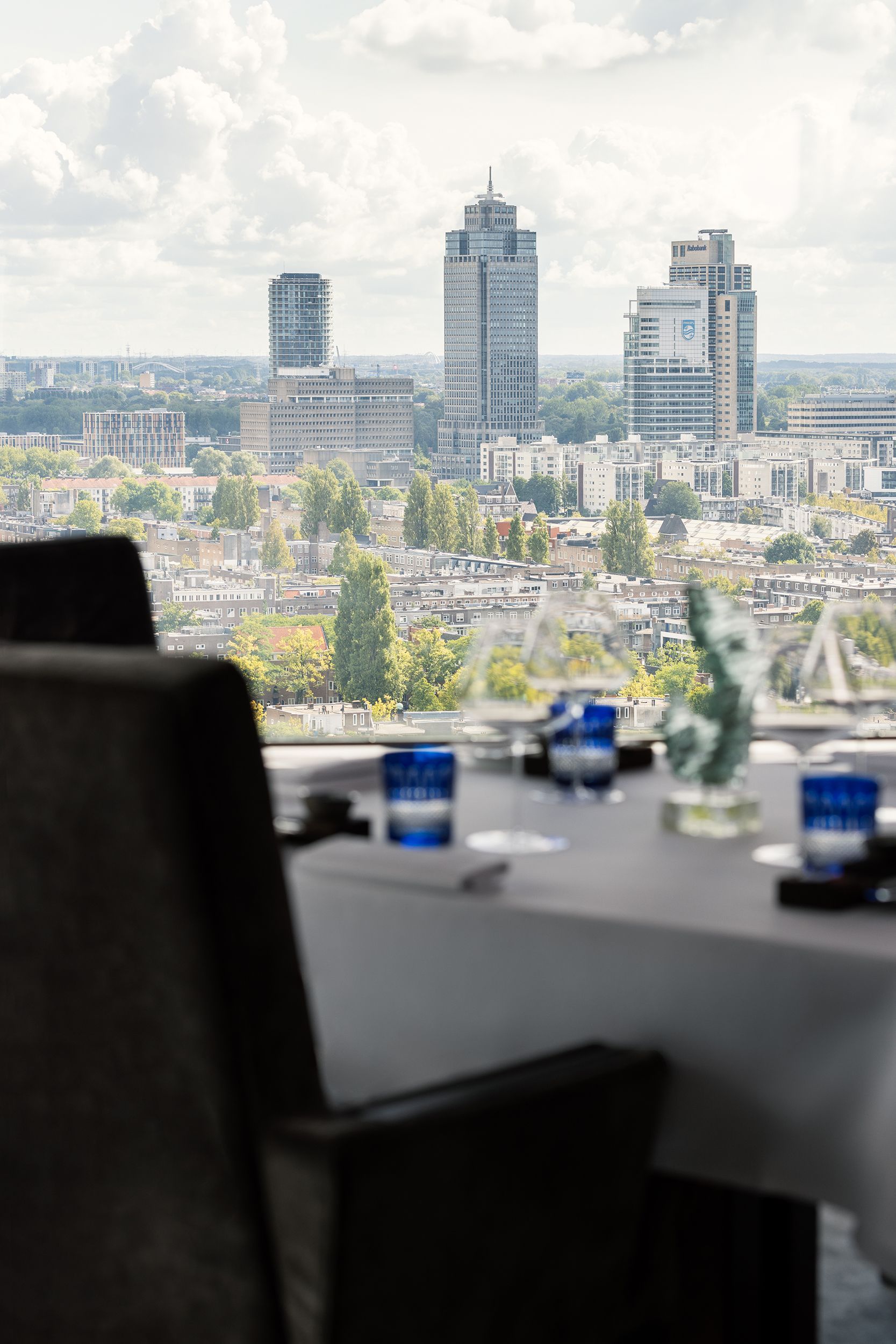 A table with a view of a city and a chair in the foreground.