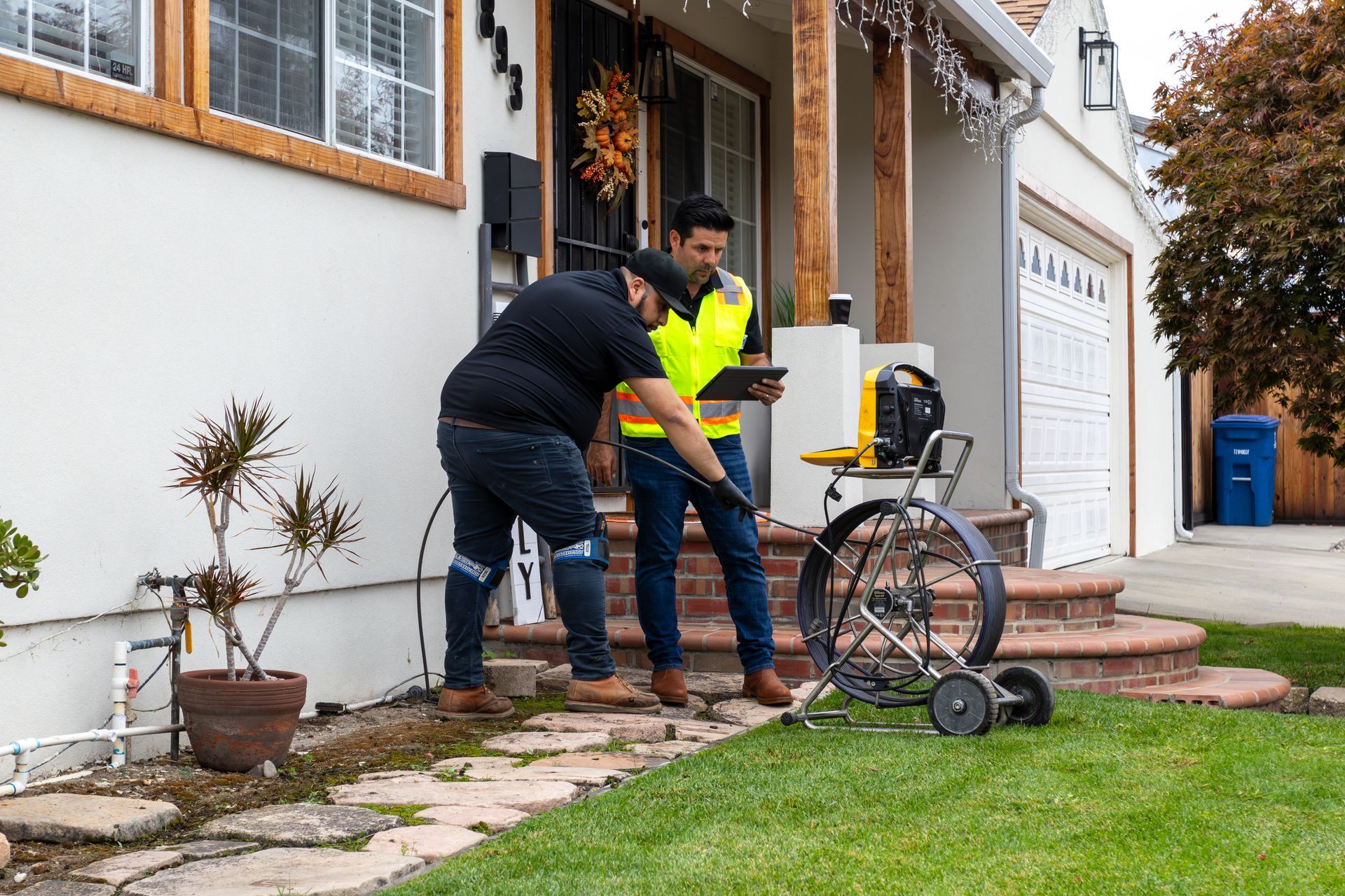 Two workers using a tool by a house exterior