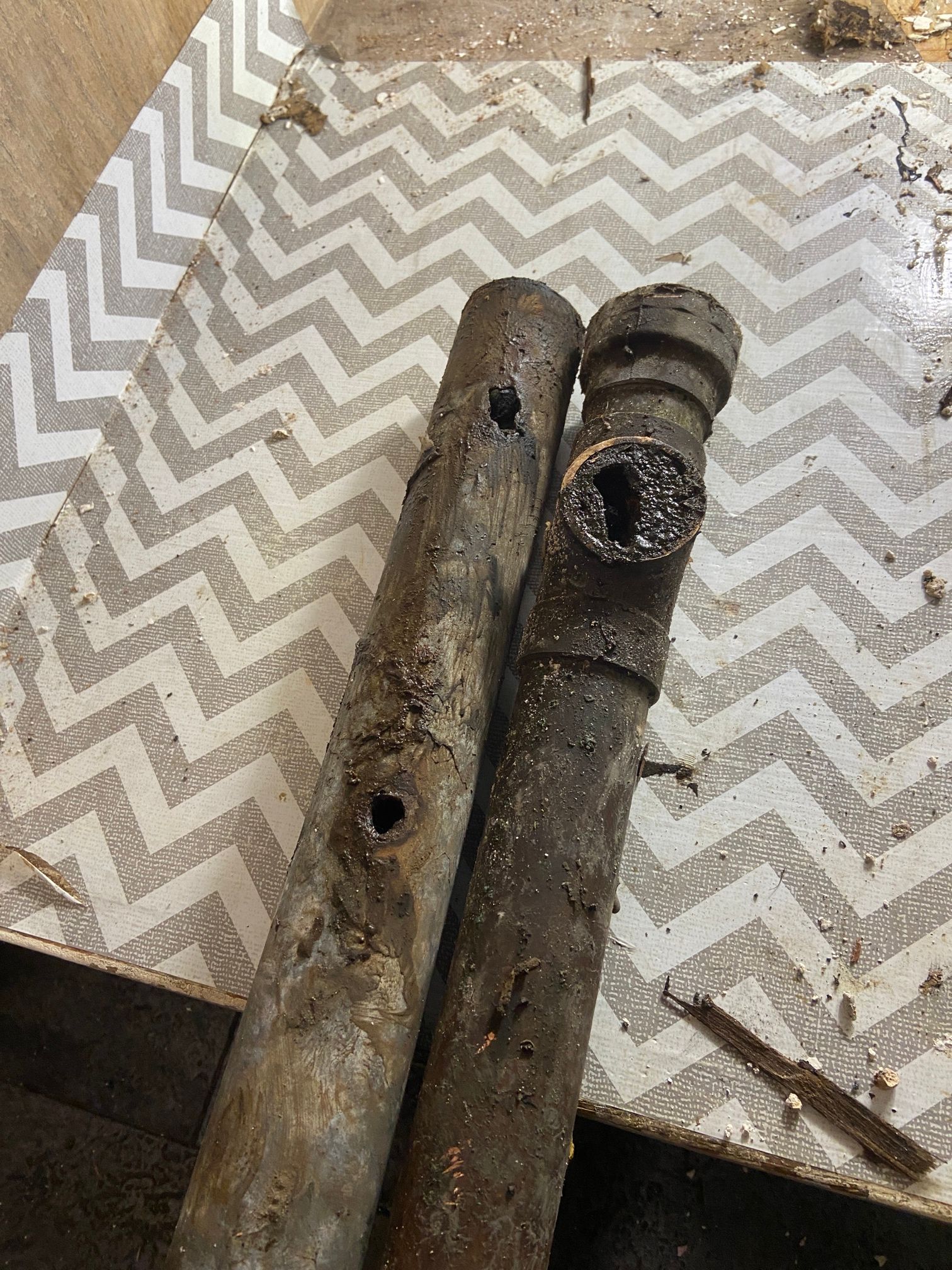 Two rusted metal pipes on a zigzag-patterned fabric surface