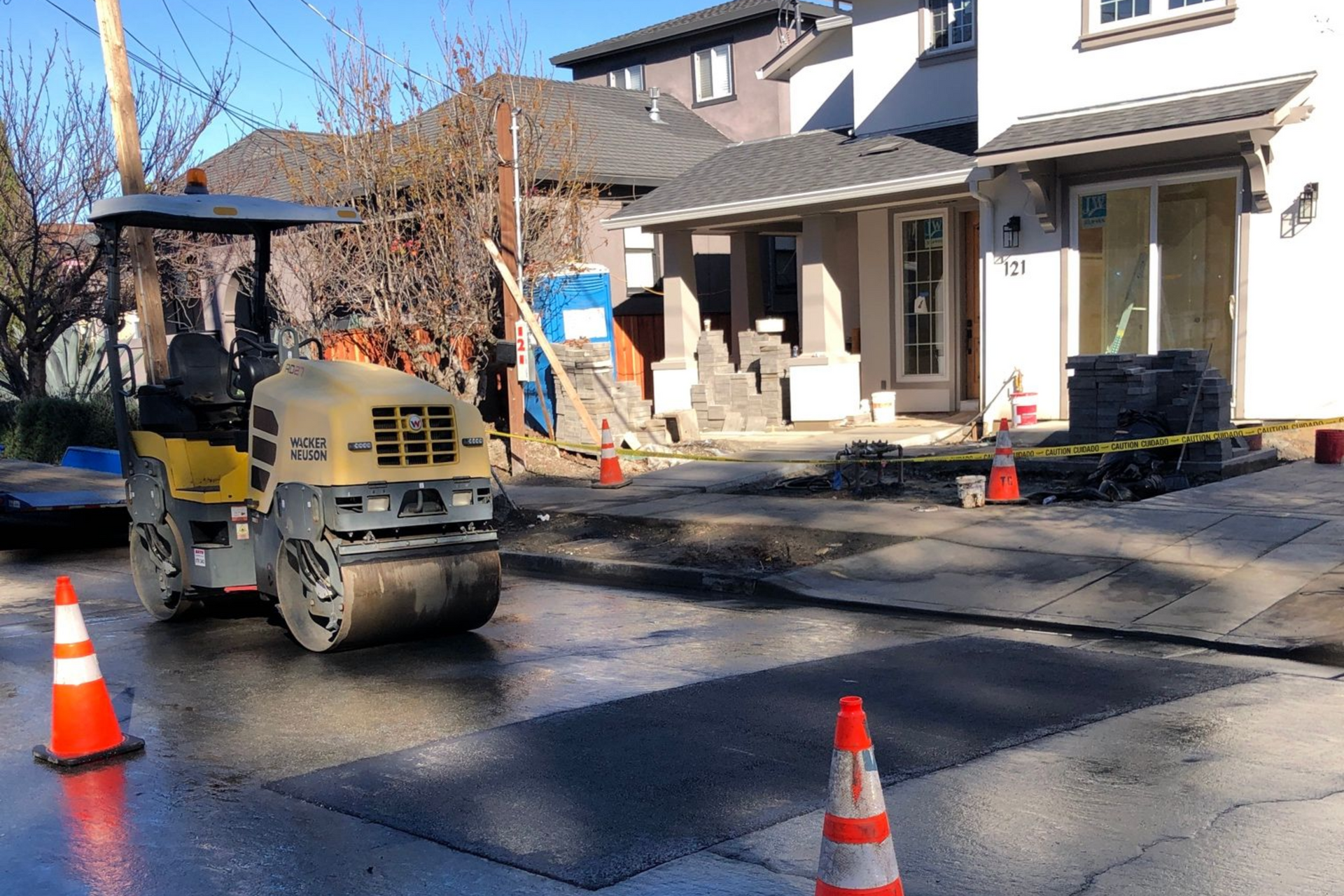 Road construction with a paving machine and orange cones in a suburban street