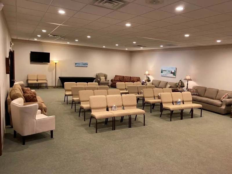 Funeral home waiting area with beige chairs, sofas, and muted decor.