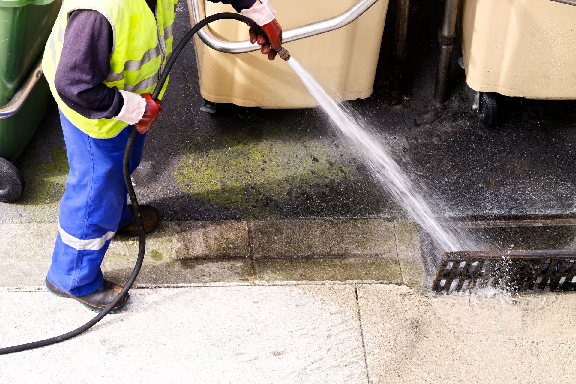 A man is cleaning a drain with a high pressure hose.