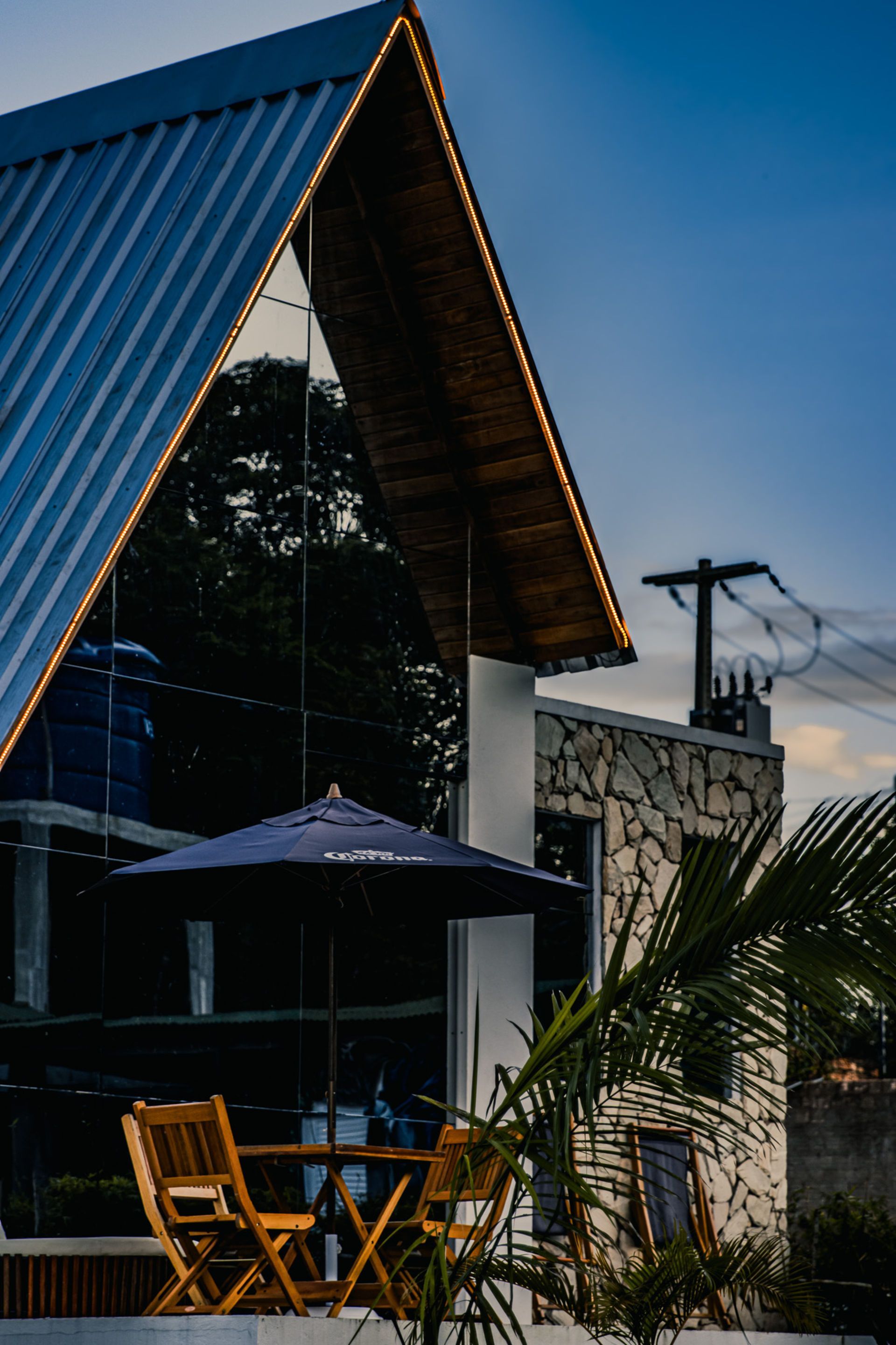A-frame building with glass walls, umbrella-covered outdoor seating, and a stone facade section.
