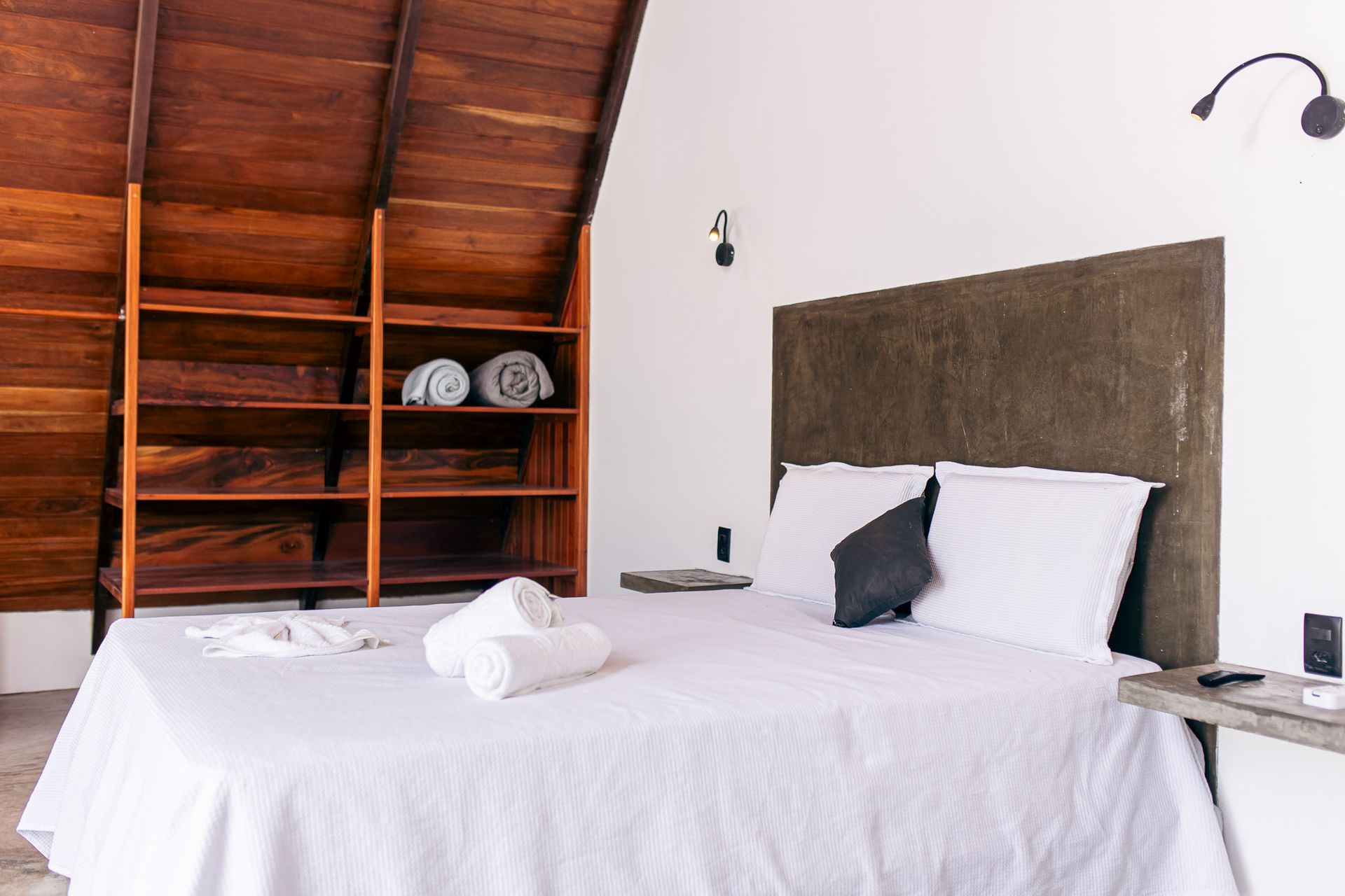 Bedroom with wooden shelving, white bed, and brown headboard.