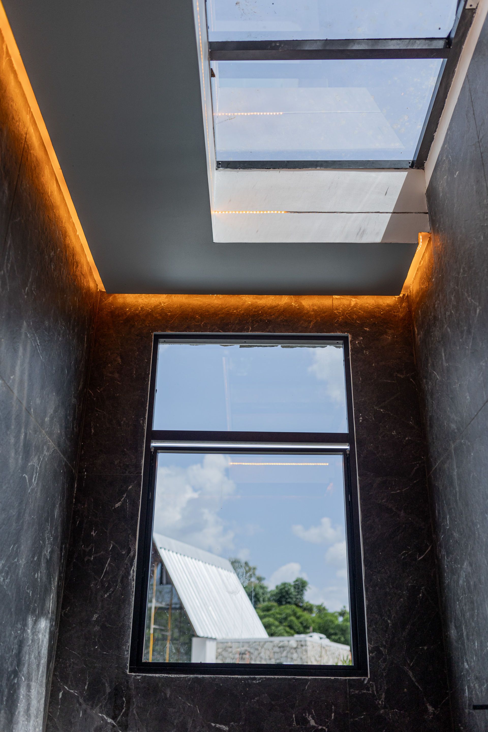 Interior shot: Dark walls, window reflecting building, skylight above, and ceiling lighting.