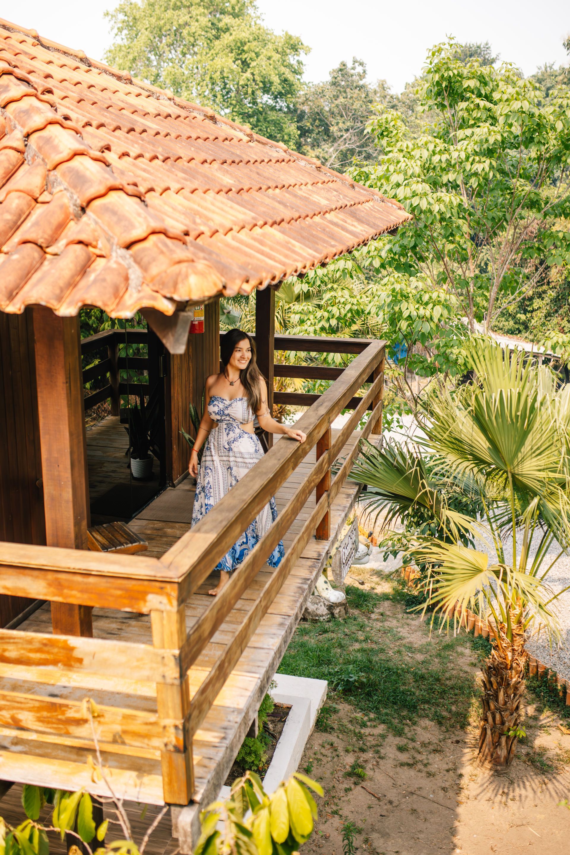 Woman smiling, using a phone, lying on a bed in a bedroom with decorative wall art.