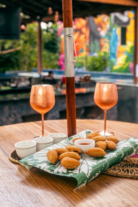 Table with snacks, two copper wine glasses, and dipping sauces. Outdoor setting, colorful mural background.