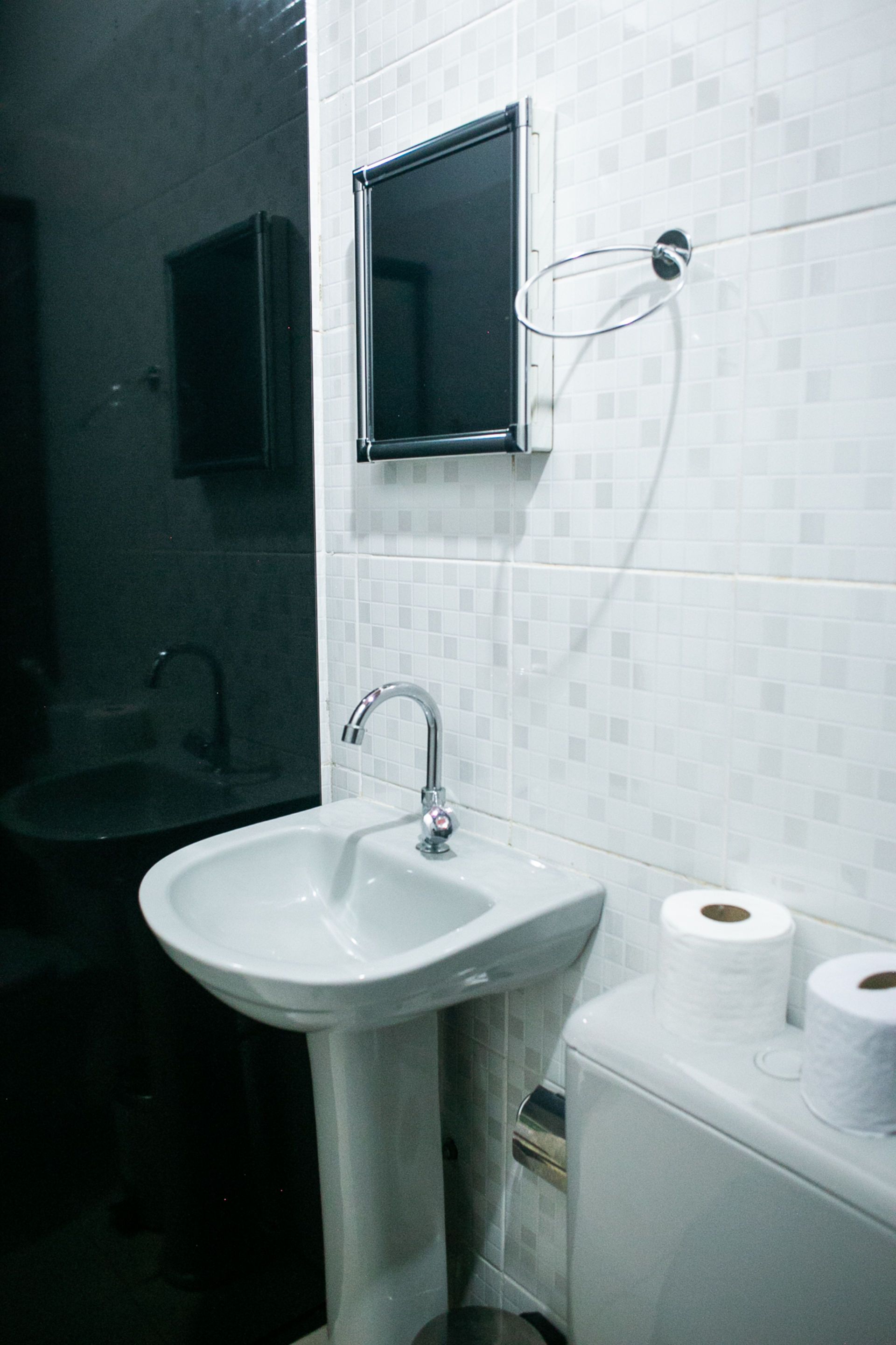 Bathroom with sink, mirror, toilet, and two rolls of toilet paper on the right.