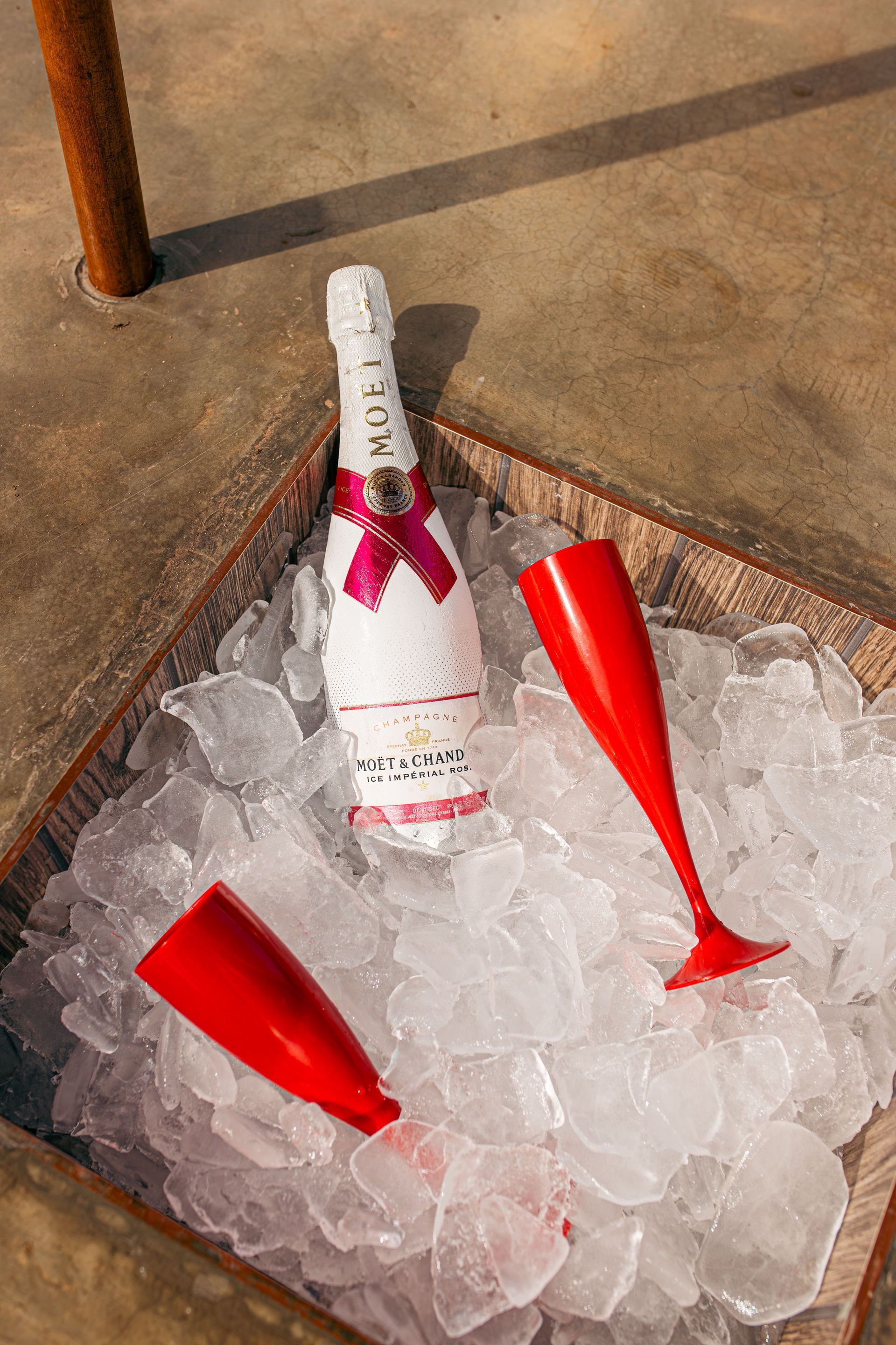 Bottle of Moët champagne with red flutes in ice.