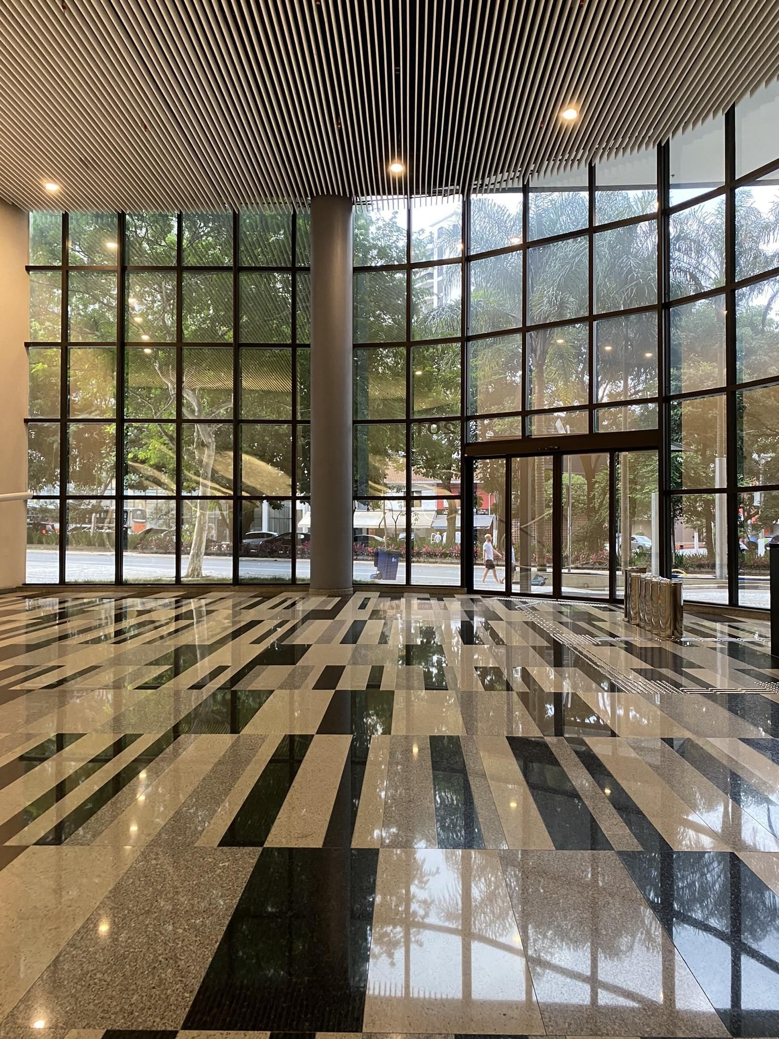 Uma sala grande com muitas janelas e piso de mármore.