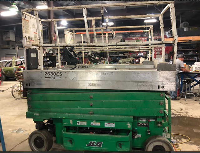 A green scissor lift is sitting in a garage.