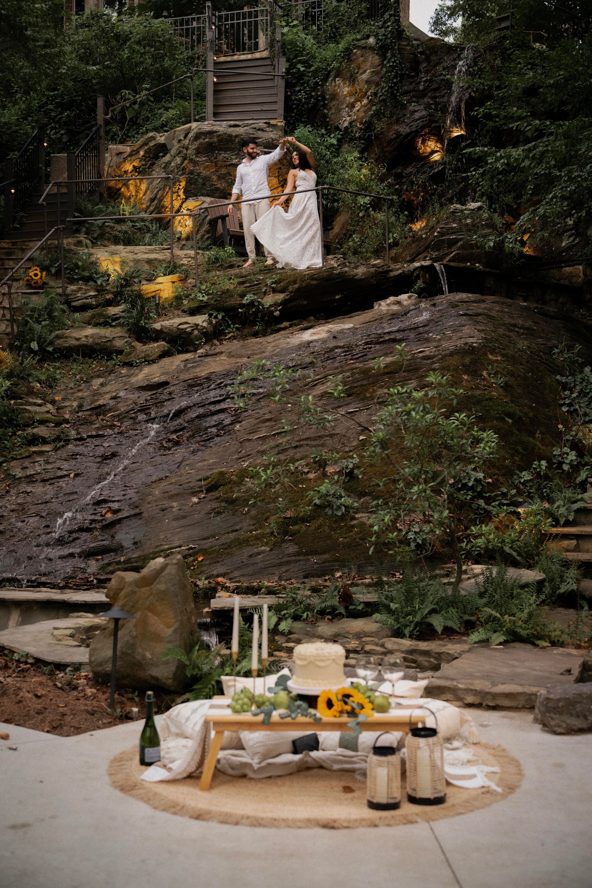 Groom lifts bride during a wedding photo shoot on stone steps in a park.