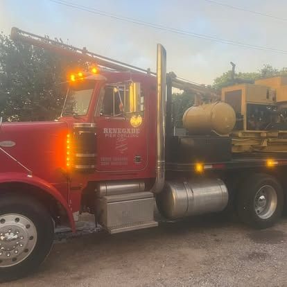 A red truck with a yellow tank on the back is parked in a parking lot.
