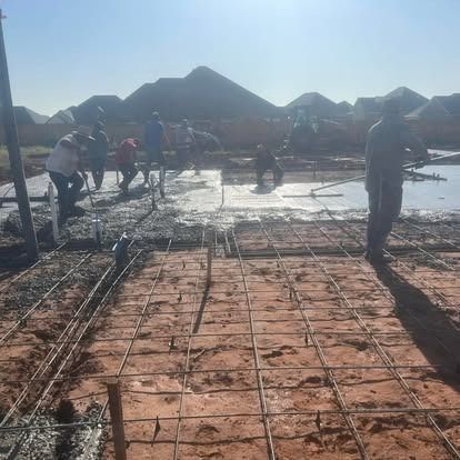 A group of construction workers are working on a concrete floor.