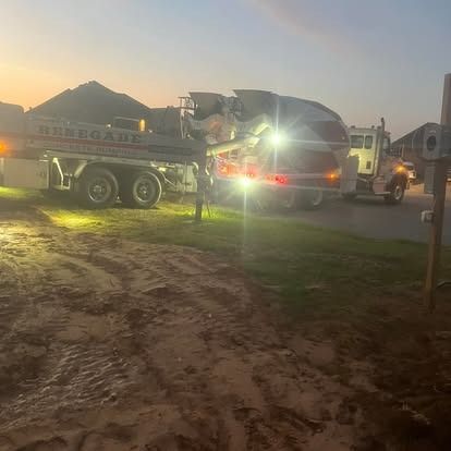 A concrete mixer truck is parked on the side of the road at night.