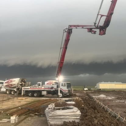 A concrete pump is pouring concrete into a pile of dirt.