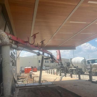 A concrete mixer truck is parked under a wooden roof.
