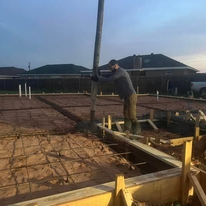 A man is pumping concrete into a foundation at a construction site.