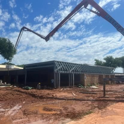 A concrete pump is being used to pour concrete into a building under construction.
