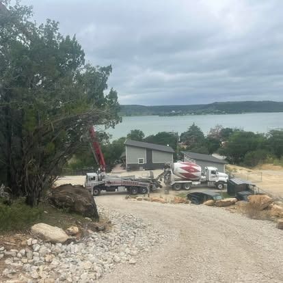 A concrete mixer truck is parked in a gravel lot next to a lake.