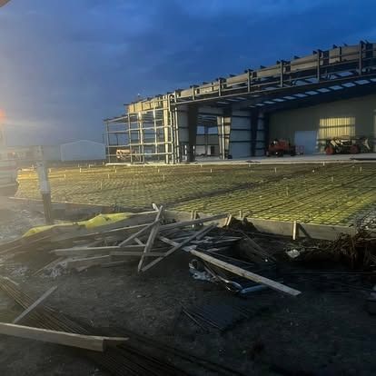 A building under construction with a lot of wood laying on the ground in front of it.