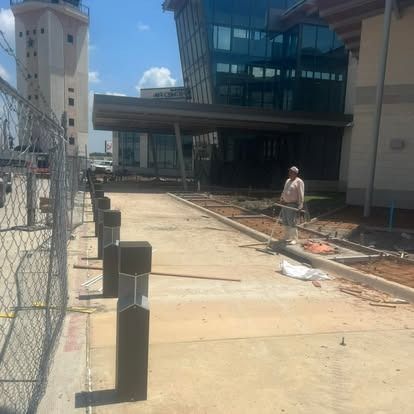 A man is standing on a sidewalk in front of a building.