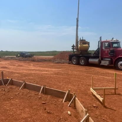 A red semi truck is parked in a dirt field.