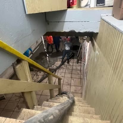 A staircase leading up to a basement with a hole in the wall.
