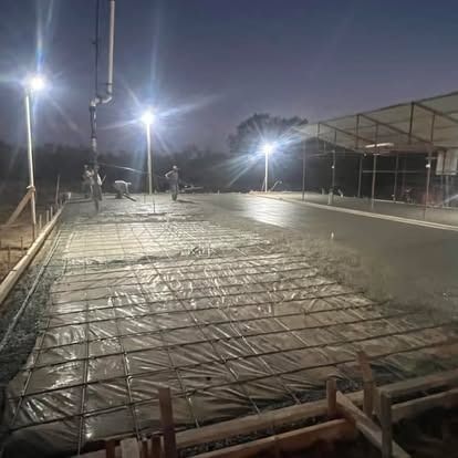 A concrete driveway is being poured at night.