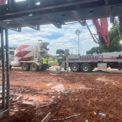 A concrete mixer truck is driving down a dirt road.