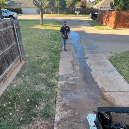 A man is standing on a sidewalk next to a fence.