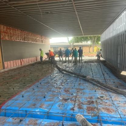 A group of people are standing on top of a blue concrete floor.