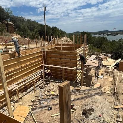 A group of construction workers are working on a building on top of a hill.