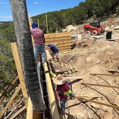 A group of construction workers are working on a building on top of a hill.