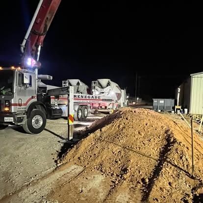 A concrete pump truck is pumping concrete into a pile of dirt.