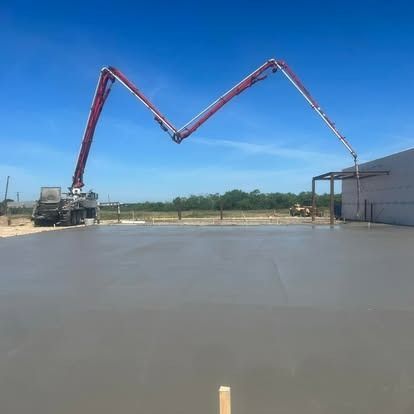 A concrete pump is being used to pour concrete into a parking lot.