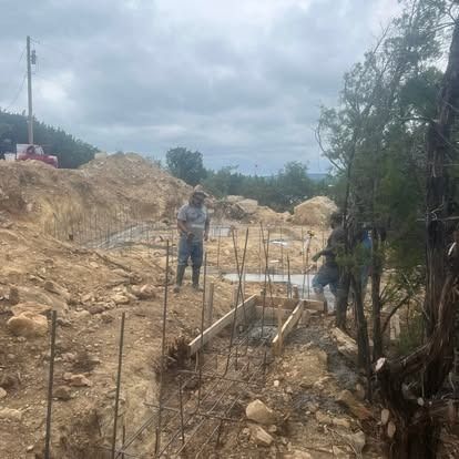 A group of men are standing in a dirt field.
