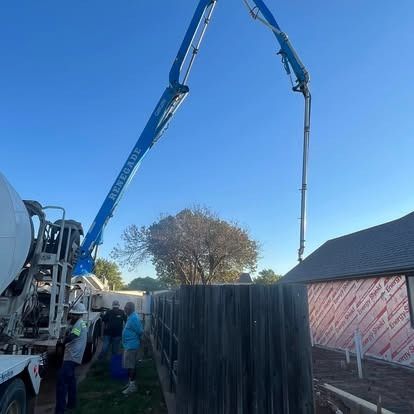 A concrete pump is being used to pour concrete into a fence.