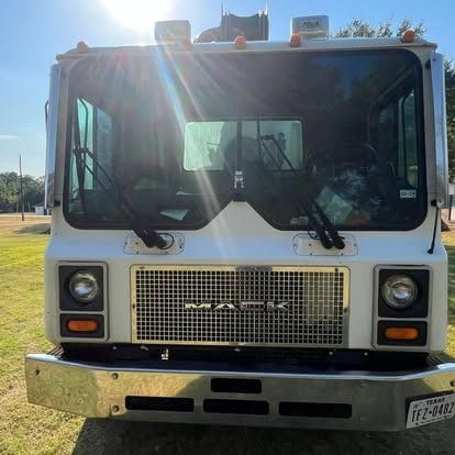 A white mack truck is parked in a grassy field.